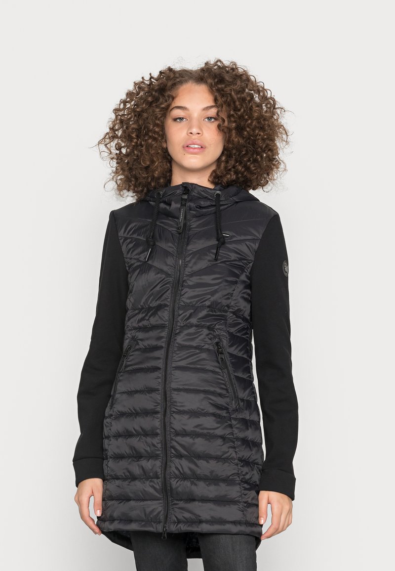 Gilet piumino nero con chiusura a zip e cappuccio, caratterizzato da un design trapuntato. Le maniche sono in tessuto nero, in contrasto con il corpo lucido.