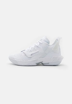 Baskets blanches de sport avec dessus en mesh, semelle texturée, design à lacets et languette à l’arrière, montrées de profil sur fond neutre.