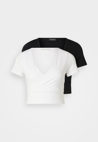 Dos tops recortados, uno blanco y uno negro. Ambos presentan un diseño de cuello en V y mangas cortas, hechos de un tejido suave con un sutil brillo.