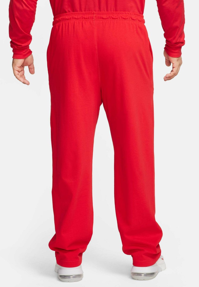 Czerwone dresy z elastycznym pasem, luźny krój i zwężane mankiety. Wykonane z miękkiego materiału. Widoczne detale szycia.