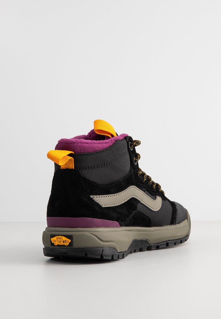 Zapatilla alta que presenta un tejido en negro y gris, detalles en púrpura, un tirador amarillo en el talón y cordones dorados, con una suela negra resistente.