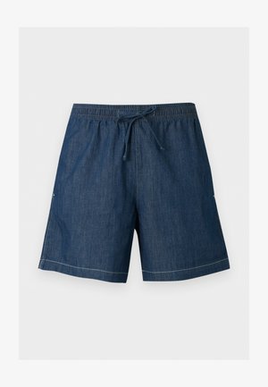 Tumed sinised teksapüksid, millel on elastne vöökoht ja esiteljed, sirge lõige ning nähtav valge õmblusääre ääres.