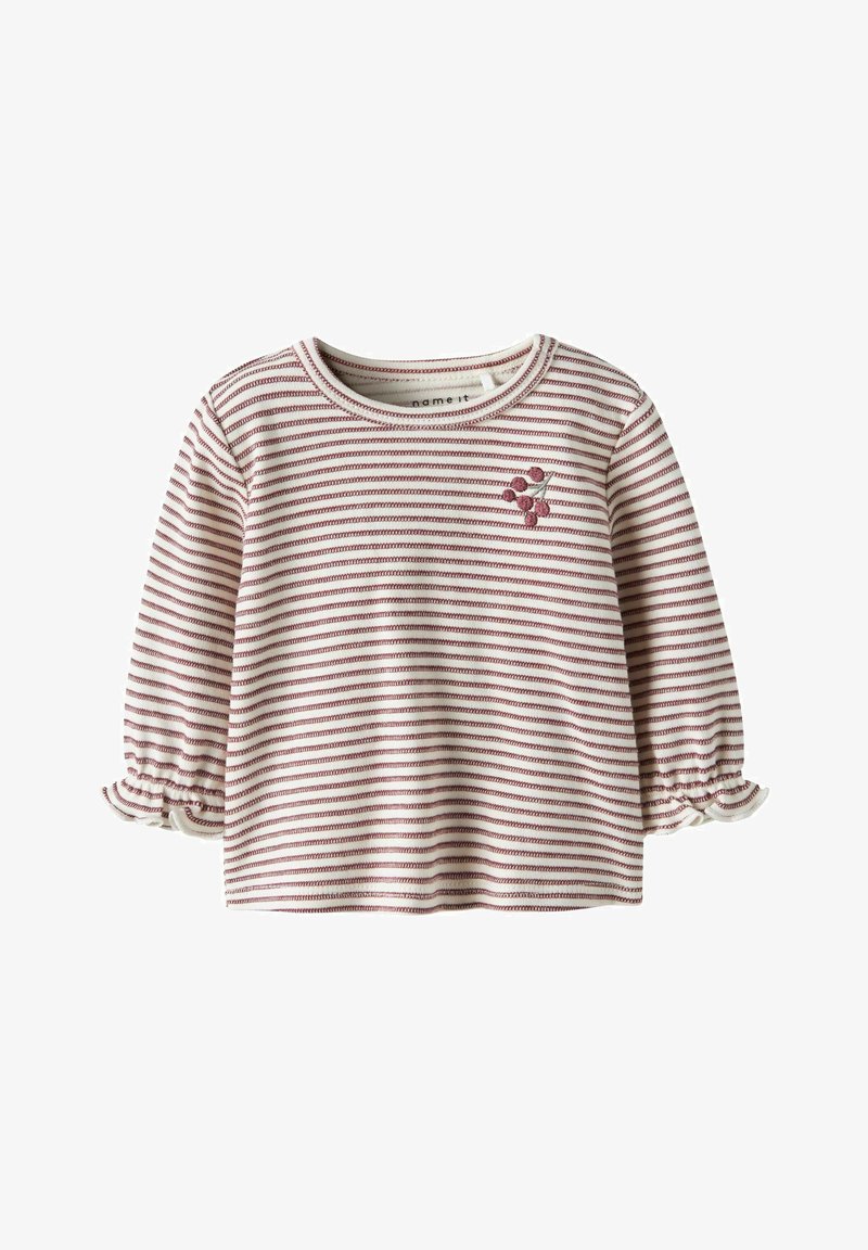 Ilgomis rankovėmis kreminės spalvos palaidinė su plonomis horizontaliomis raudonomis juostelėmis, raukšlėtais rankogaliais ir mažu raudonų uogų klasteriu siuvinėtu kairėje krūtinės pusėje.