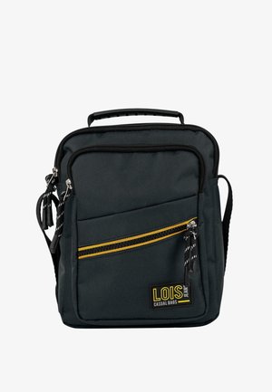 Mochila de tela negra con una franja vertical amarilla. Cuenta con asa superior, correa ajustable y bolsillo delantero con cremallera y tassels.