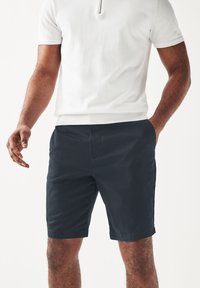 Pantaloni corti blu navy con vita piatta, tasche laterali e vestibilità casual. Realizzati in tessuto leggero per comfort e traspirabilità.