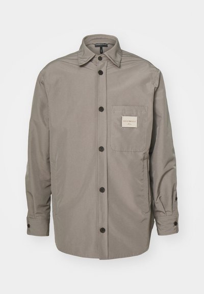 Pilkas mygtukų užsegimas švarkas, pagamintas iš sklandaus audinio; turi krūtinės kišenę su etikete, ilgas rankoves ir klasikinio kirpimo apykaklę.