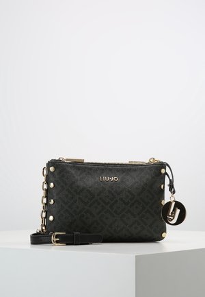 Sac bandoulière noir Liu Jo avec clous dorés, anse chaîne, breloque logo et texture à motifs subtils sur une surface blanche.