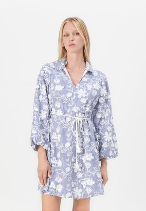 Randig blå och vit klänning med blommig broderi, krage och åtsittande midja. Har långa, puffadeärmar och en lagerpäls.