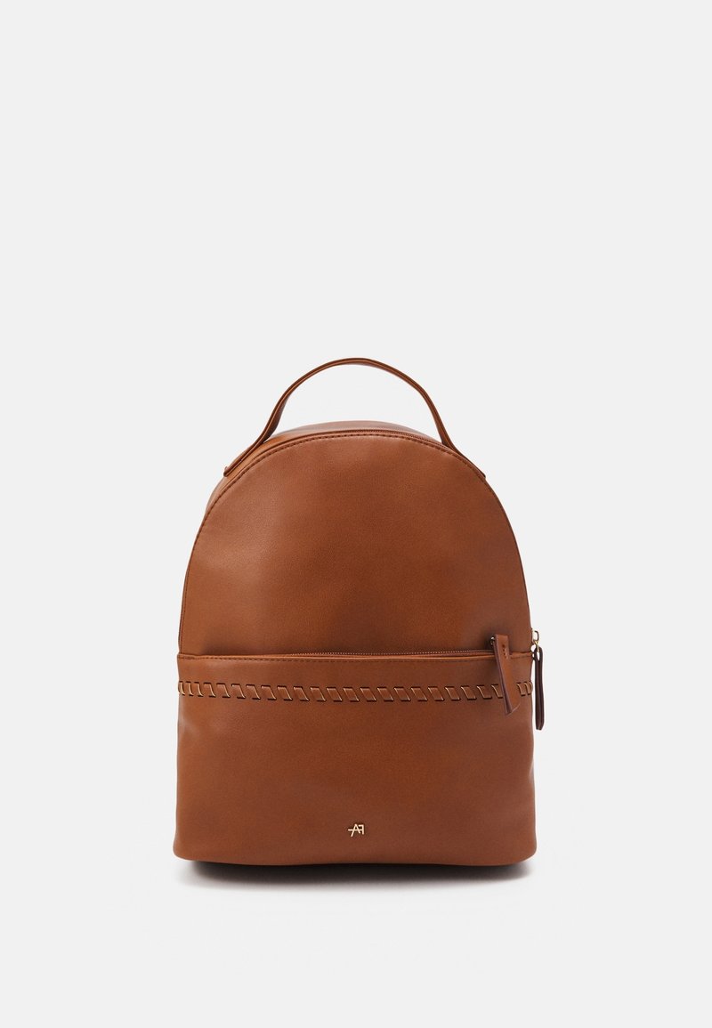 Sac à dos en cuir marron avec une forme arrondie, doté d'une poignée supérieure et d'un accent cousu à l'avant. Fermeture éclair.