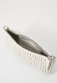 Biely tkaný kožený clutch s uzáverom na zips, obsahujúci strieborné kovanie a hladký interiér, s priehradkami na karty a plochou kapsou.