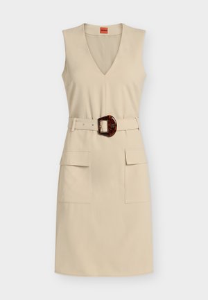 Αμάνικο μπεζ φόρεμα μέχρι το γόνατο με V-λαιμόκοψη, εμπρόσθιες τσέπες με καπάκι και ταιριαστή ζώνη με μεγάλη αγκράφα από χελώνα.