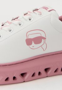 Witte leren sneaker met een roze zool en accenten. Voorzien van een bedrukte gezicht met zonnebril en een gestructureerd, geventileerd zoolontwerp.