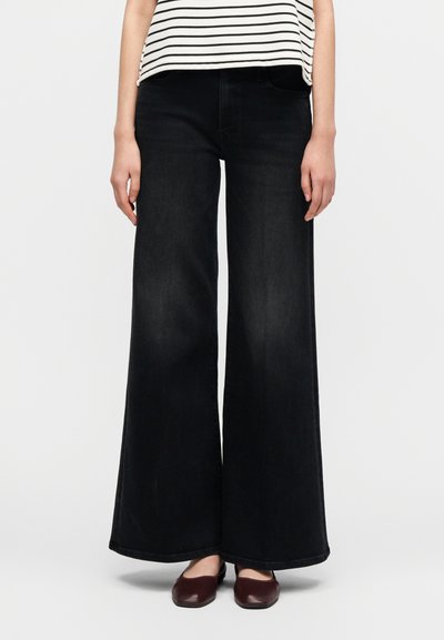 Μαύρο τζιν με φαρδύ παντελόνι από ντένιμ, με κλασικό σχέδιο πέντε τσεπών, ίσια κοπή και διακριτική ξεθωριασμένη υφή. Συνδυασμένο με μαρόν παπούτσια.