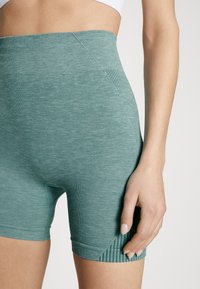 Ribbad tealfärgade cykelshorts med hög midja och texturerade detaljer på sidan, tillverkade av ett mjukt, elastiskt tyg för komfort och flexibilitet.