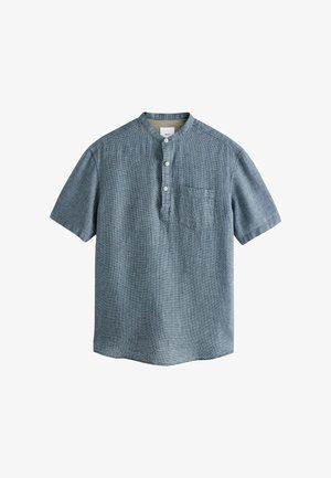 Zils krekls ar īsām piedurknēm, ar joslas apkakli, priekšējo kabatu un pogu aizdari. Izgatavots no teksturēta auduma ar delikātu rakstu.