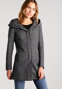 Manteau en pied de poule gris avec une grande capuche, fermeture à boutons sur le devant, poches latérales et coupe ajustée, fabriqué en tissu tissé au toucher doux.