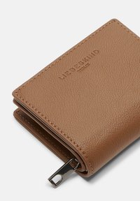 Portafoglio compatto in pelle marrone con texture, dettagli di cucitura e zip argentata, con il marchio "Liebeskind Berlin" impresso sulla parte anteriore.