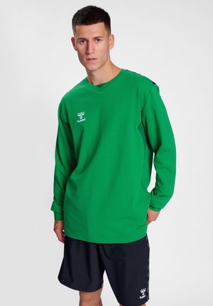 Grünes langärmliges Crewneck-Shirt mit V-Ausschnitt, das ein Logo auf der Brust und schwarze Akzente an den Schultern aufweist.