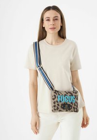 Umhängetasche mit Leopardenmuster aus Stoff, mit blauer "FOCUS"-Aufschrift, schwarzem Zubehör und einem gestreiften verstellbaren Tragegurt.