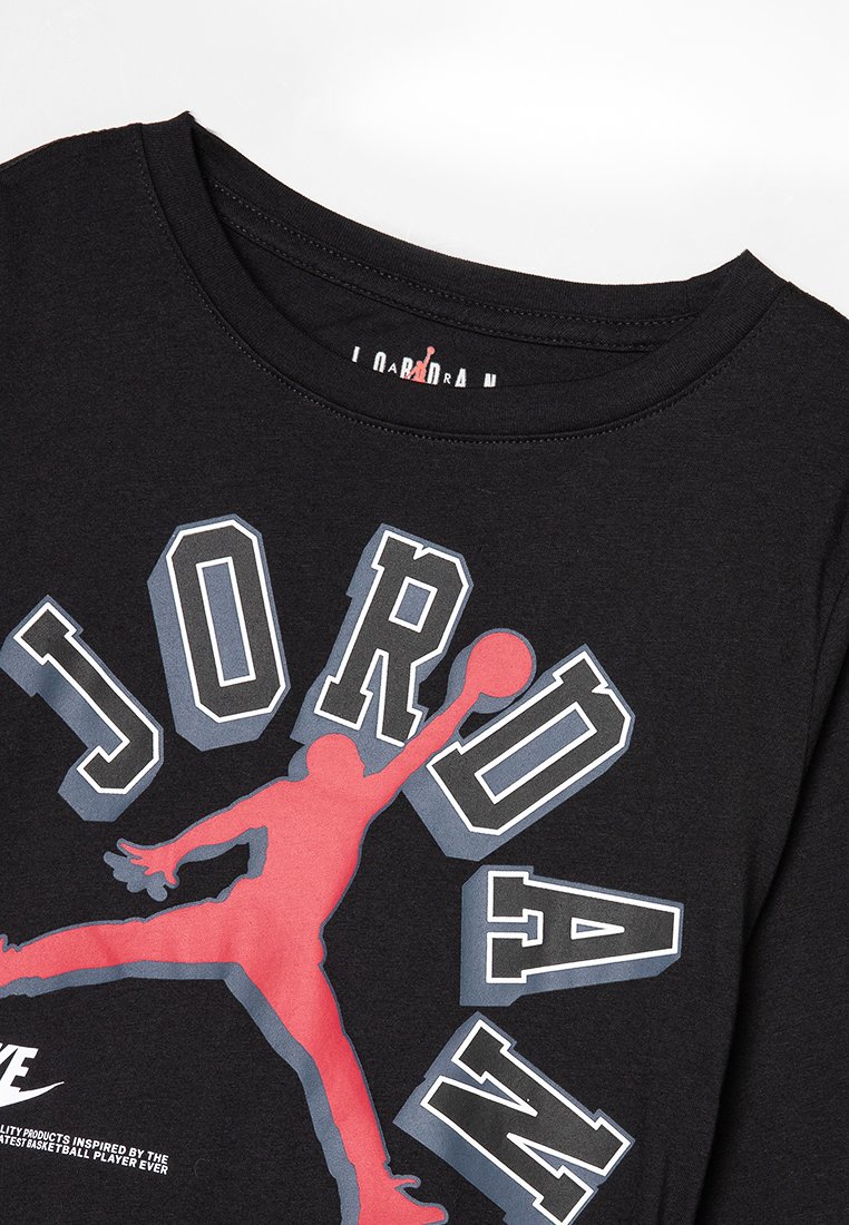 Camiseta negra con una gran silueta roja de un jugador de baloncesto saltando, rodeada de letras en negrita en blanco y gris que dicen "JORDAN."