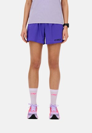 Legs of person wearing purple athletic shorts, white socks with pink "cep" logo, pink and white running shoes, and black wristwatch on left wrist.