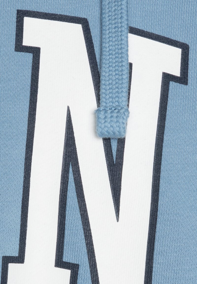 Hellblauer Hoodie mit einem auffälligen weißen "N"-Logo mit dunkelblauer Umrandung und strukturiertem Zugband-Detail. Weicher Stoff mit feinen Rippungen.