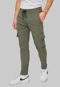 Pantalons cargo vert olive avec une coupe fuselée, taille élastique et cordon de serrage, comportant des poches latérales et une finition textile lisse.