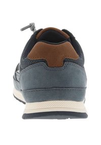 Chaussure de sport grise avec un accent en cuir brun au niveau du talon. Des panneaux en maille améliorent la respirabilité. Semelle en caoutchouc avec une bande crème clair contrastante.