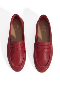 Rote Lederloafers mit strukturierten Oberflächen, quadratischer Zehenform und dekorativem Band über der Vorderseite. Braune Innensohlen mit eingeprägtem Logo. Flache Sohlen.
