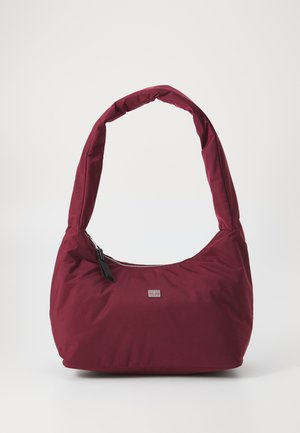 Mala de ombro bordeaux feita de tecido macio, com uma alça curva e acolchoada e um fecho zip com uma pequena etiqueta de marca na frente.