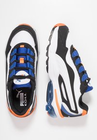 Baskets de sport blanches et noires avec des accents bleus, dotées d'une tige en mesh, d'une semelle en caoutchouc et d'un coussin d'air visible au niveau du talon.