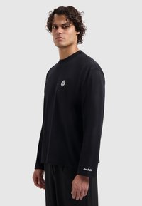 Black long-sleeve t-shirt in cotton with a round neckline, featuring a small white logo on the chest and "Pure Path" text on the sleeve.