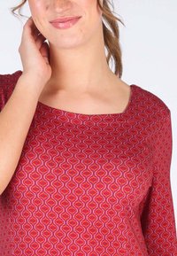 Rotes Oberteil mit quadratischem Ausschnitt, das ein welliges geometrisches Design in rosa und orange Tönen aufweist. Weicher Stoff, taillierte Silhouette.