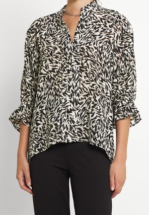 Blusa de patrón en blanco y negro con cuello en V, mangas de tres cuartos y puños con volantes. Tela ligera y fluida con un corte relajado.