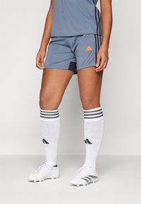 Gray athletic shorts with orange logo, striped white and black socks, and white cleats. Features a lightweight fabric and fitted design.