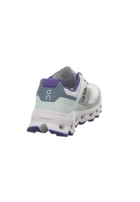 Chaussure de course avec une tige en mesh blanc, des accents bleu clair, un contrefort de talon violet et une semelle blanche texturée avec des coussinets de rembourrage visibles.