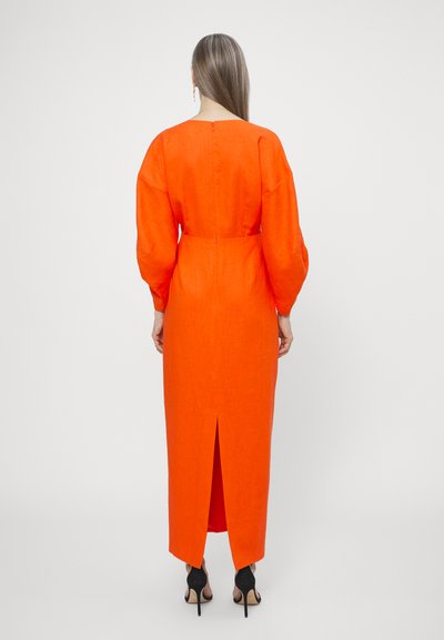 Long, form-fitting dress in bright orange linen with a back slit, wide sleeves, and a button closure. Simple, clean design with a smooth texture.