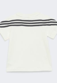 Maglietta bianca a maniche corte con scollatura rotonda, caratterizzata da tre righe orizzontali nere sulla schiena, realizzata in morbido cotone.