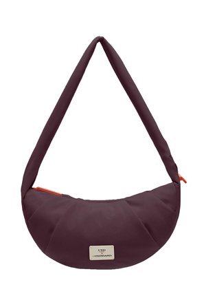 Bolso de hombro en forma de media luna de color púrpura oscuro con correa acolchada y pequeña placa de marca de metal en la parte delantera, con tiradores de cremallera naranjas.