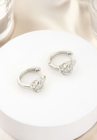 Silver hoopörhängen med en cirkulär design och en kristallprydd låsning. Slät yta med polerad finish.