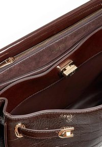 Brown synthetic handbag interior with a textured finish, featuring a gold zipper pocket and a metallic clasp closure.