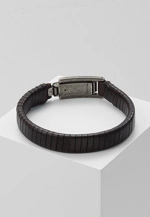 Dark brown segmented leather bracelet with a textured silver metal clasp resting on a white cube pedestal.
