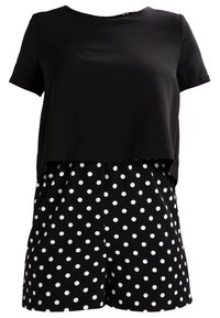 Haut noir à manches courtes associé à un short taille haute noir à pois blancs, stylé comme un ensemble coordonné deux pièces.