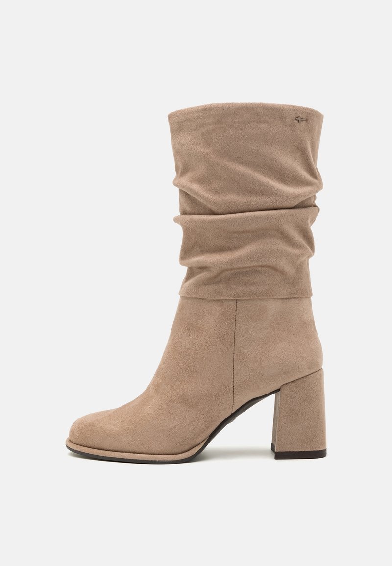 Botte mi-mollet en daim beige avec tige souple et talon bloc, détail de couture latérale et petit logo brodé près du sommet.