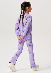 Lavendelfärgad fleece-tröja och tights, med blommiga krukmönster i grått och flerfärgade accenter, samt ribbade muddar och midja.