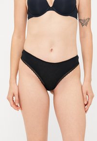 Black bikini-style underwear made from soft fabric. Features lace trim along the waistband and leg openings. Smooth texture, high-rise design.
