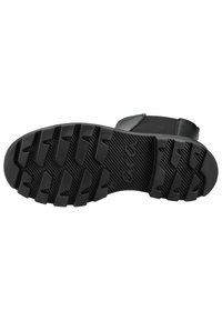 Calzado negro con suela de goma resistente que presenta surcos de tracción profundos. La parte superior es de un material liso con un diseño minimalista.