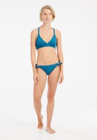 Tyrkysový bikini set s trojcípejším braletovým topom a zodpovedajúcimi nízkymi nohavičkami s viazacími detailmi na bokoch, vyrobený z hladkého, elastického materiálu.