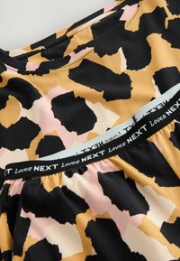 Abito per bambini con stampa leopardata astratta in nero, beige e rosa, caratterizzato da una vita elastica con il testo "Loves NEXT".