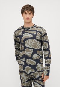 Camisa atlética de mangas longas com um padrão de camuflagem em tons de castanho e azul-marinho, feita de um material liso e elástico.